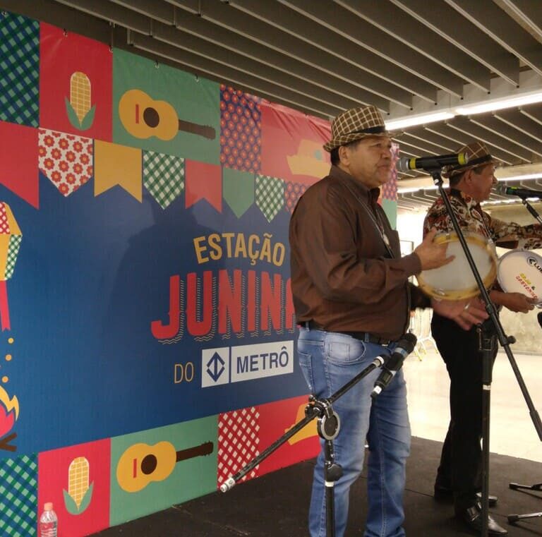Dupla de repentistas com imagem de festa junina no fundo